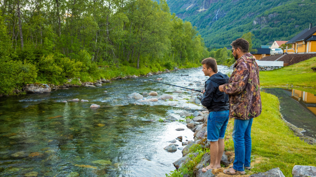 Roldal, Norway - 26.06.2018: Father and son are fishermans fly fishing in river near Rodal town in Norway