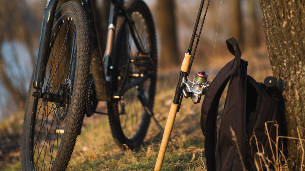 fishing rod. fishing backpack and the bike on the background of the river