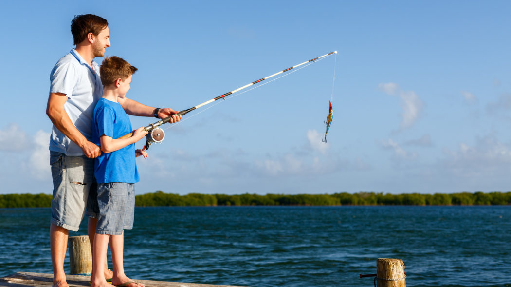 Father and son fishing together by the ocean