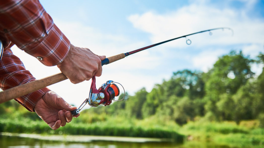 Fishing. Fisherman holding spinning reel and rod while