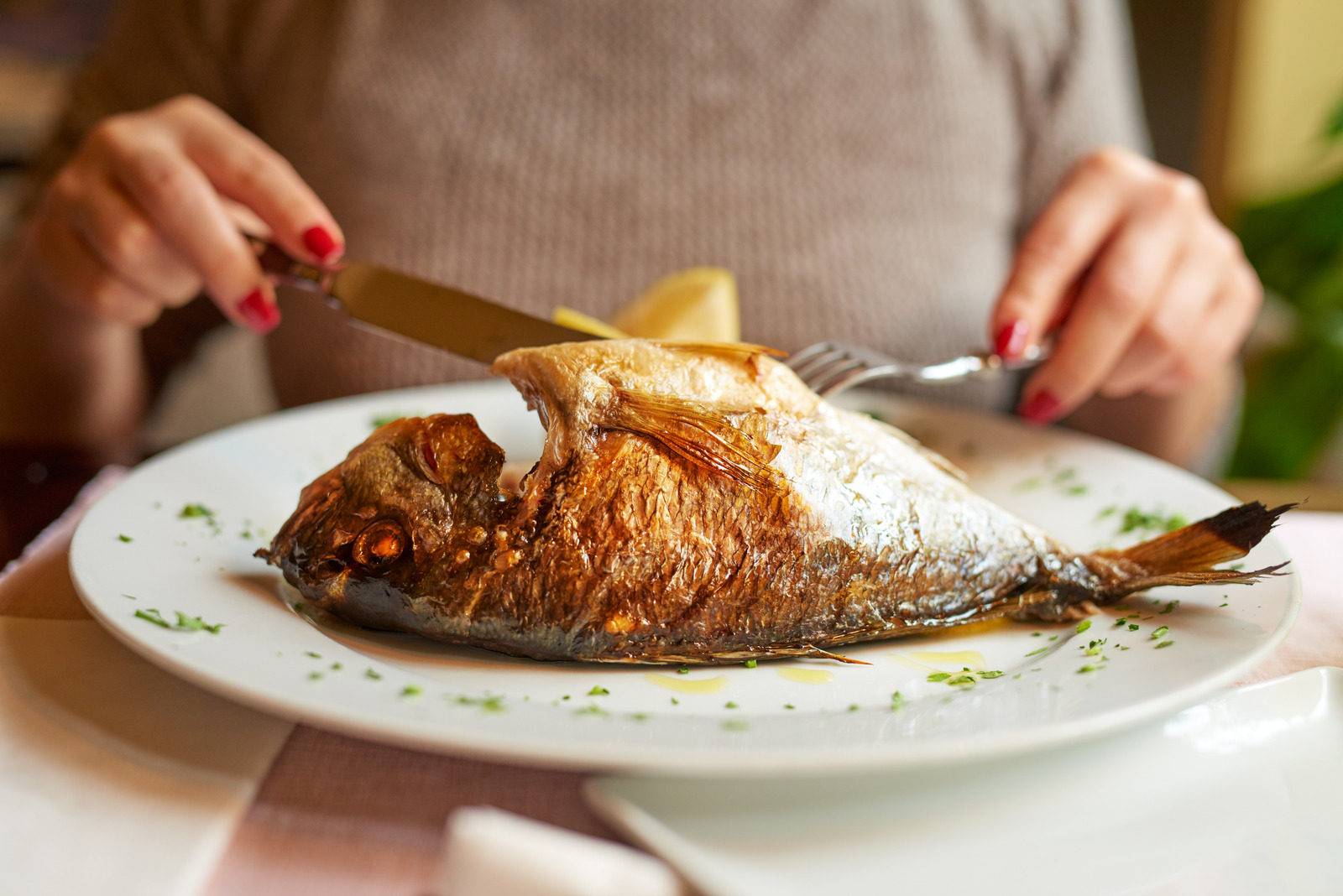 fish in plate, young woman preparing to eat it.lifestyle concept.