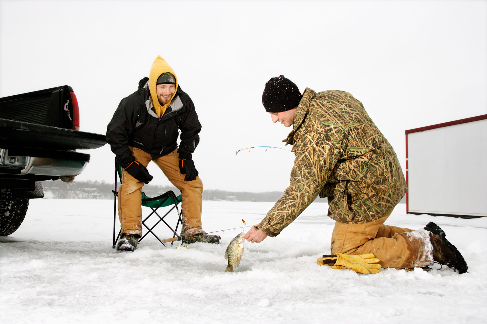 Two young men ice fishing in a winter environment. Horizontal shot.